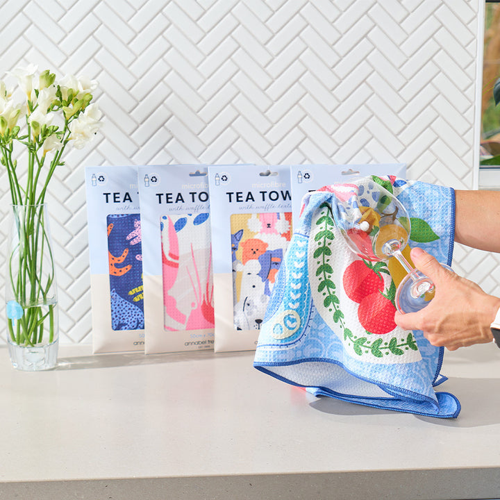 Set of tea towels with colorful designs on a kitchen counter.