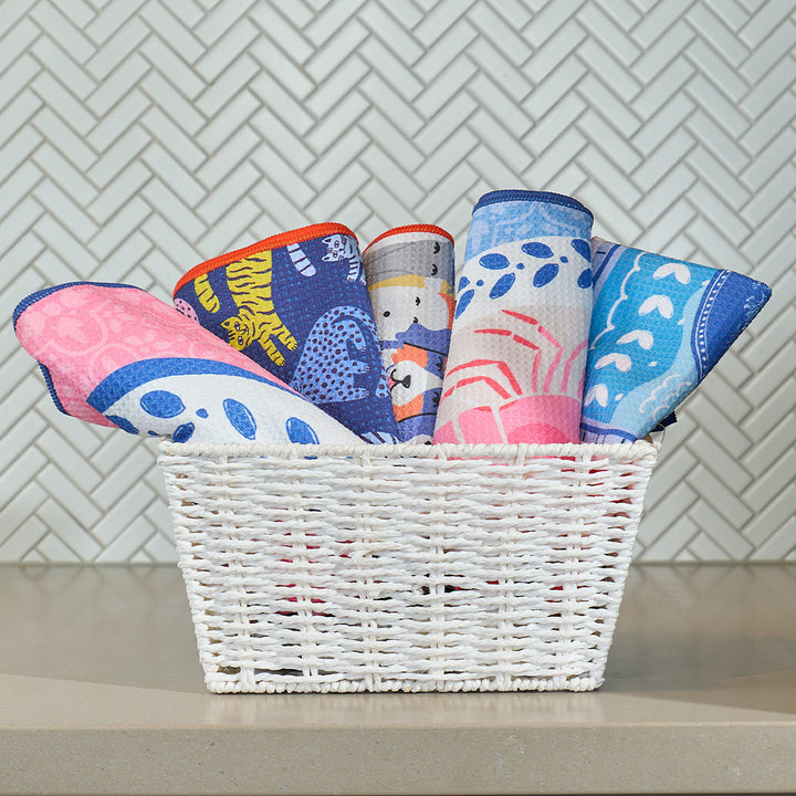 Colorful hand towels in a white basket against a tiled wall.