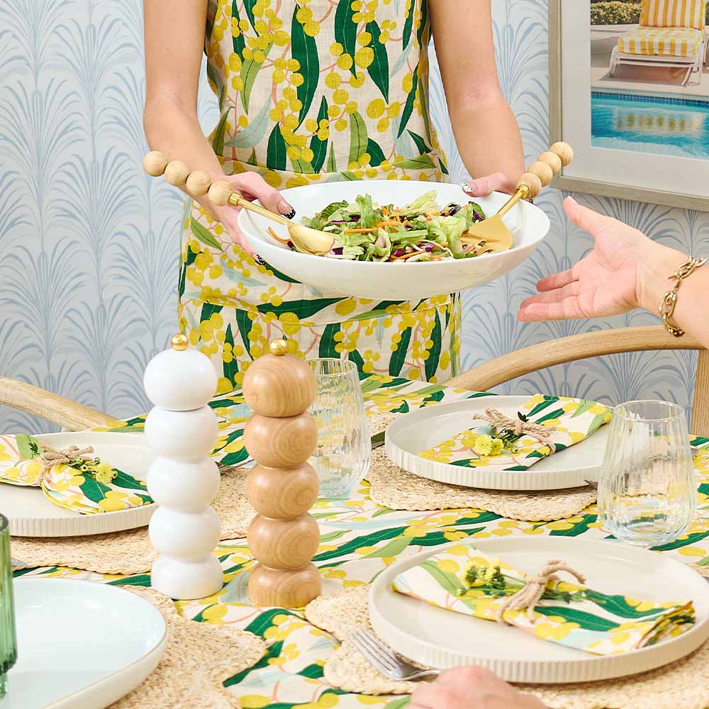 Person serving salad at a table with a colorful tablecloth and decor.
