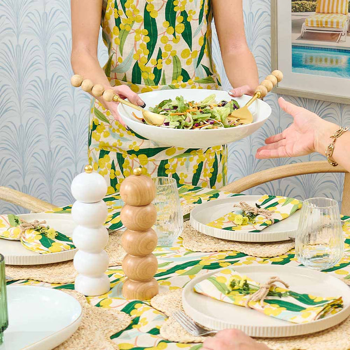 Person serving salad at a table with a colorful tablecloth and decor.