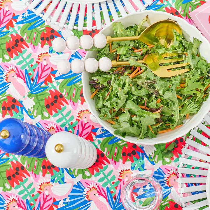 Colorful salad bowl with orb salas servers  on a vibrant, patterned tablecloth