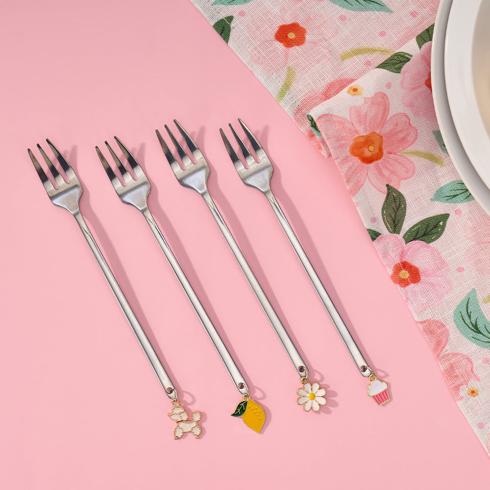 Set of four decorative forks with charms on a pink background