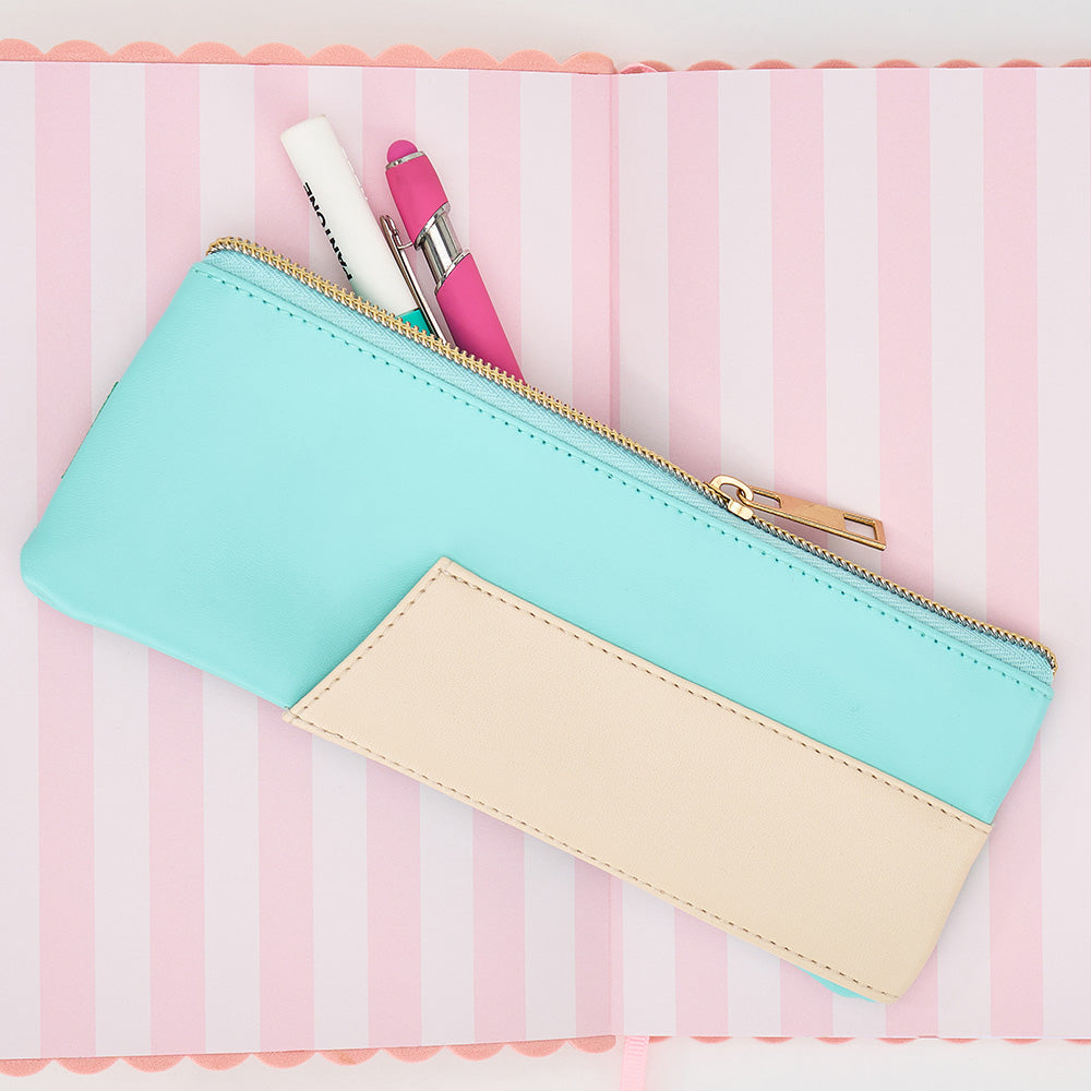 Two-tone pencil case with a gold zipper on a pink and white striped background