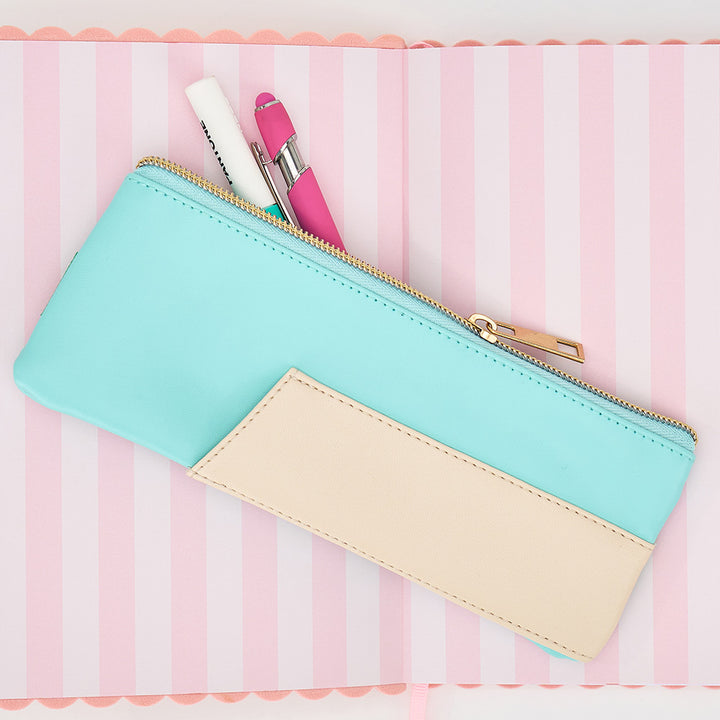 Two-tone pencil case with a gold zipper on a pink and white striped background