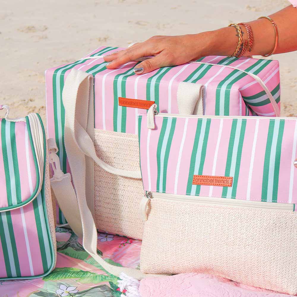 Striped bags with a hand reaching for one of them on a light wooden surface.