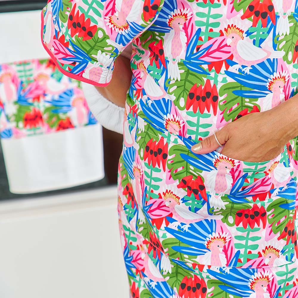 Colorful apron with tropical pattern worn by a person, with a blurred indoor background.