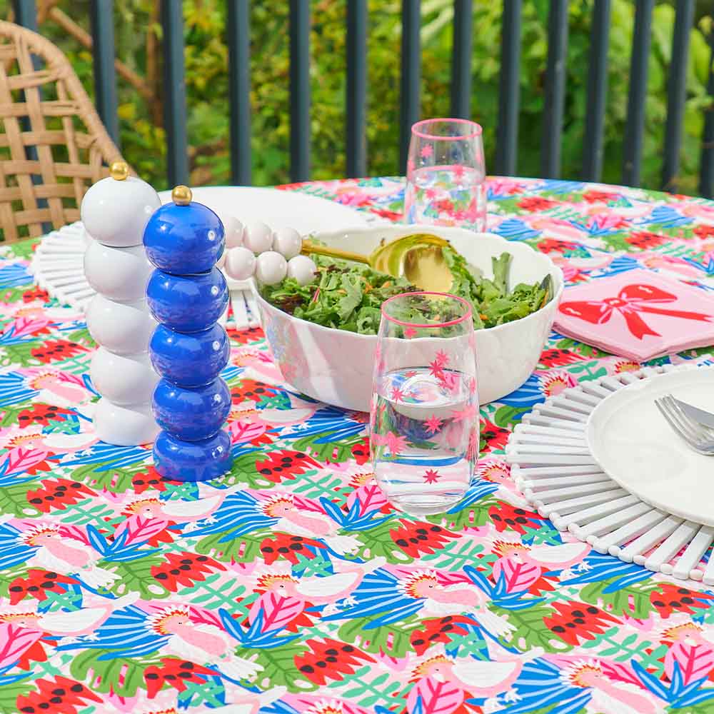 Colorful tablecloth with a floral pattern on a dining table with a salad and glasses.