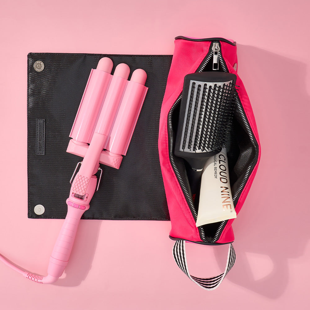 Pink hair curling iron and brush set with a pink case on a pink background