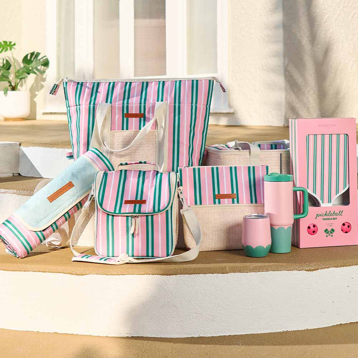 Collection of pink and green striped bags and accessories on a wooden surface.