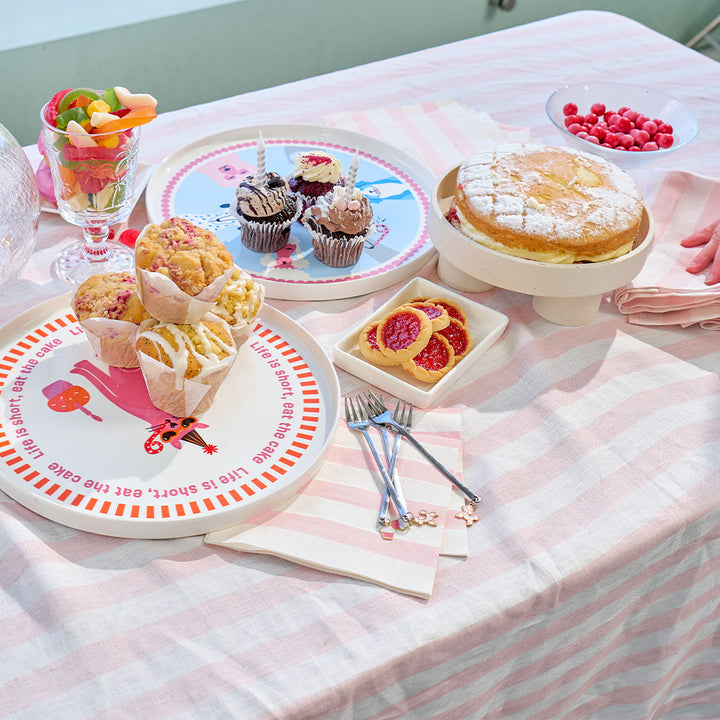 Table with various pastries and desserts on a pink stripe tablecloth