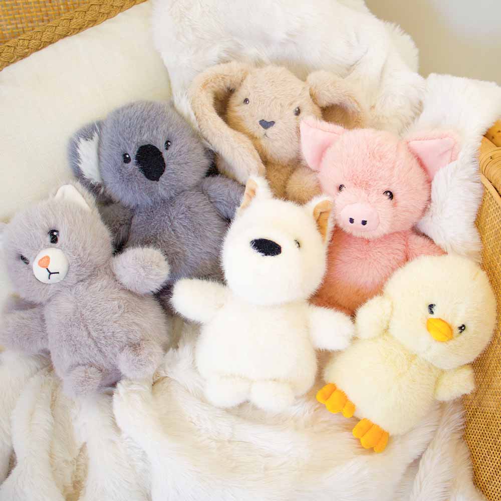 Collection of plush toys including a koala, bear, pig, and duck on a soft surface.