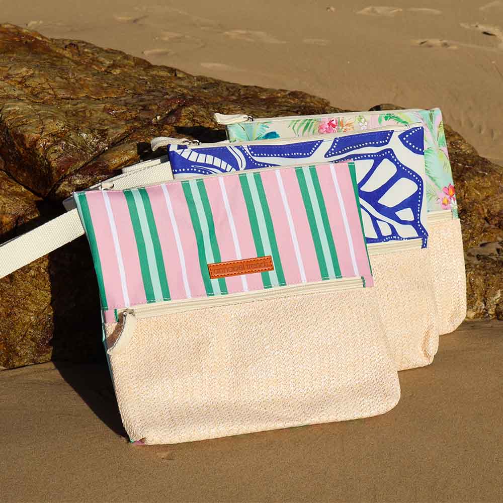 Three pouches with different designs on a sandy surface