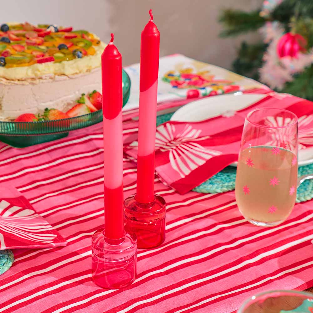 Red and white candles on a table with a cake and glass of champagne.