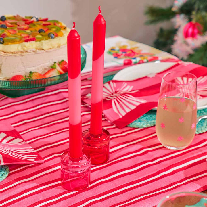 Red and white candles on a table with a cake and glass of champagne.