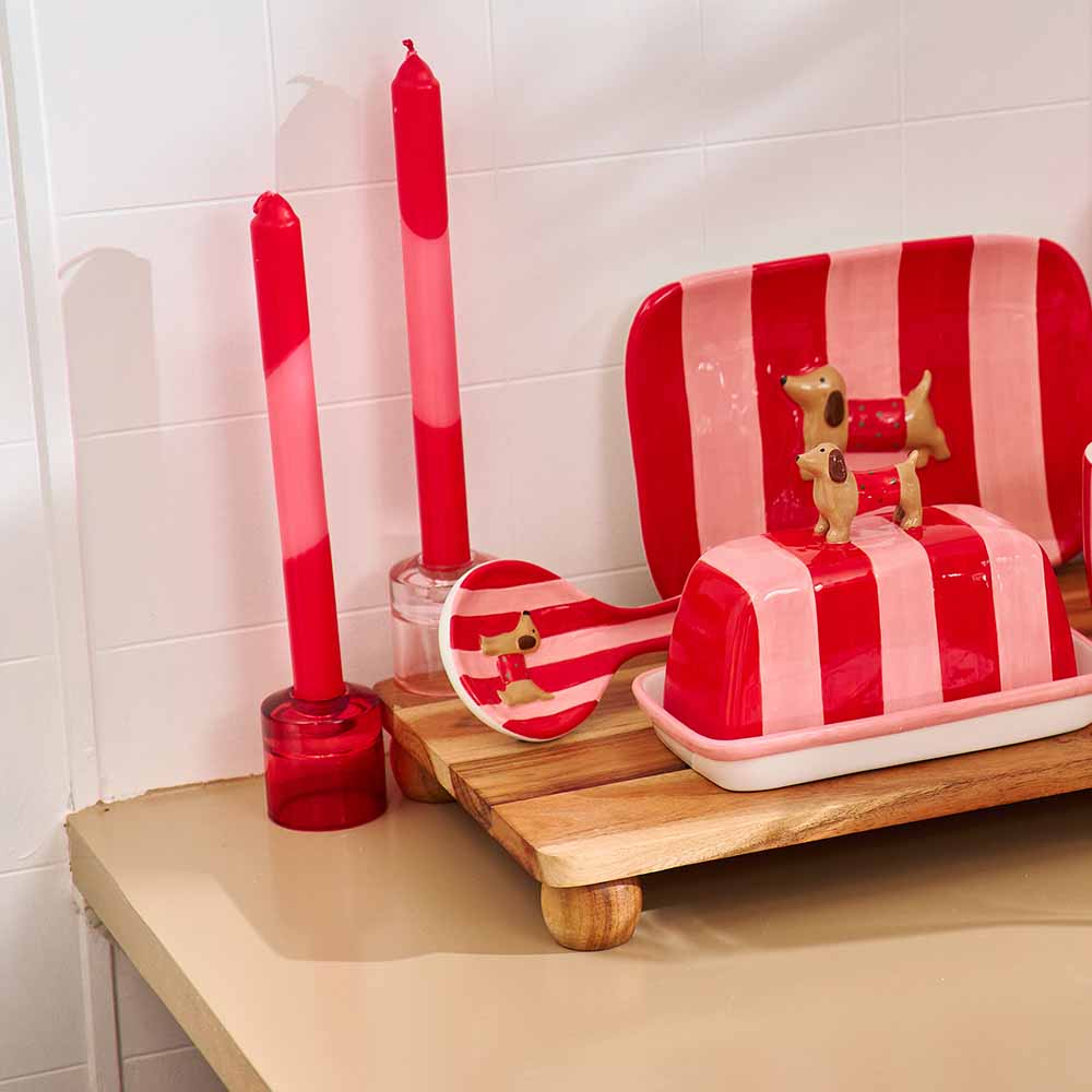 Red and white striped dish rack with a small dog figurine on a tiled bathroom counter.