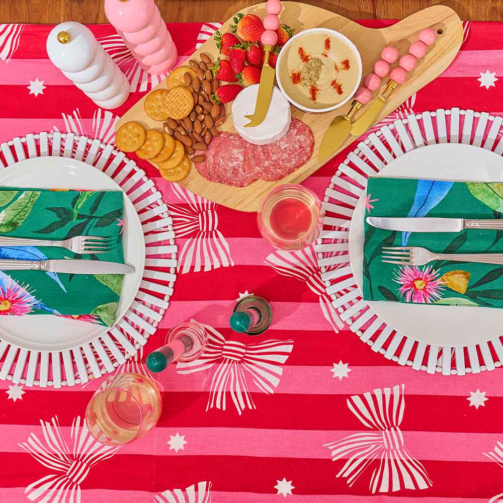 red pink striped tablecloth with printed white bows with a full table setting