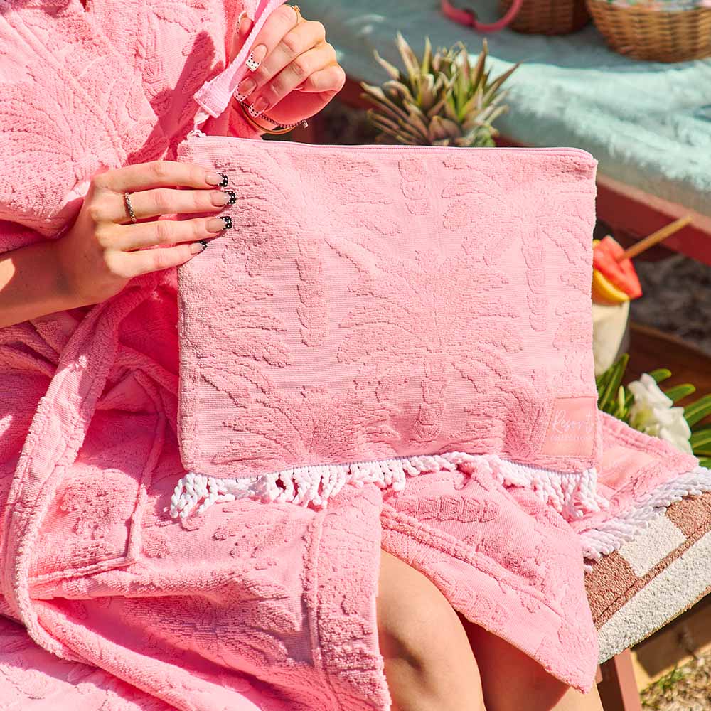 Person holding a pink textured clutch with a blurred outdoor background