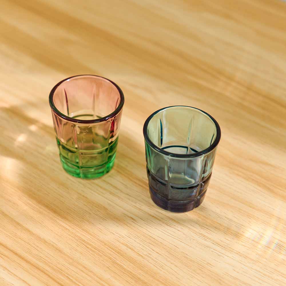 Two glass shot glasses on a wooden surface