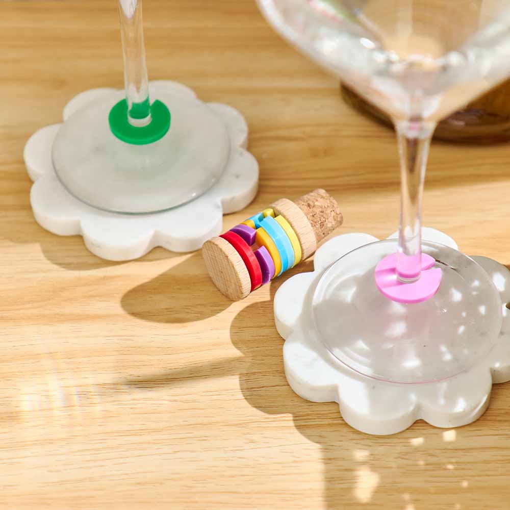 Colorful wine glass charms on a wooden table with glasses.