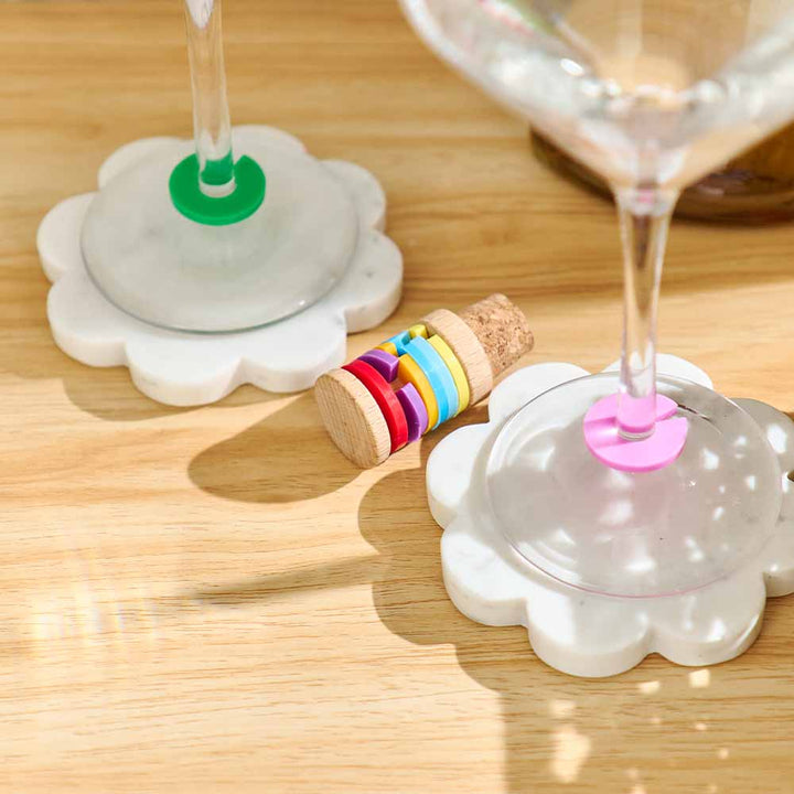 Colorful wine glass charms on a wooden table with glasses.