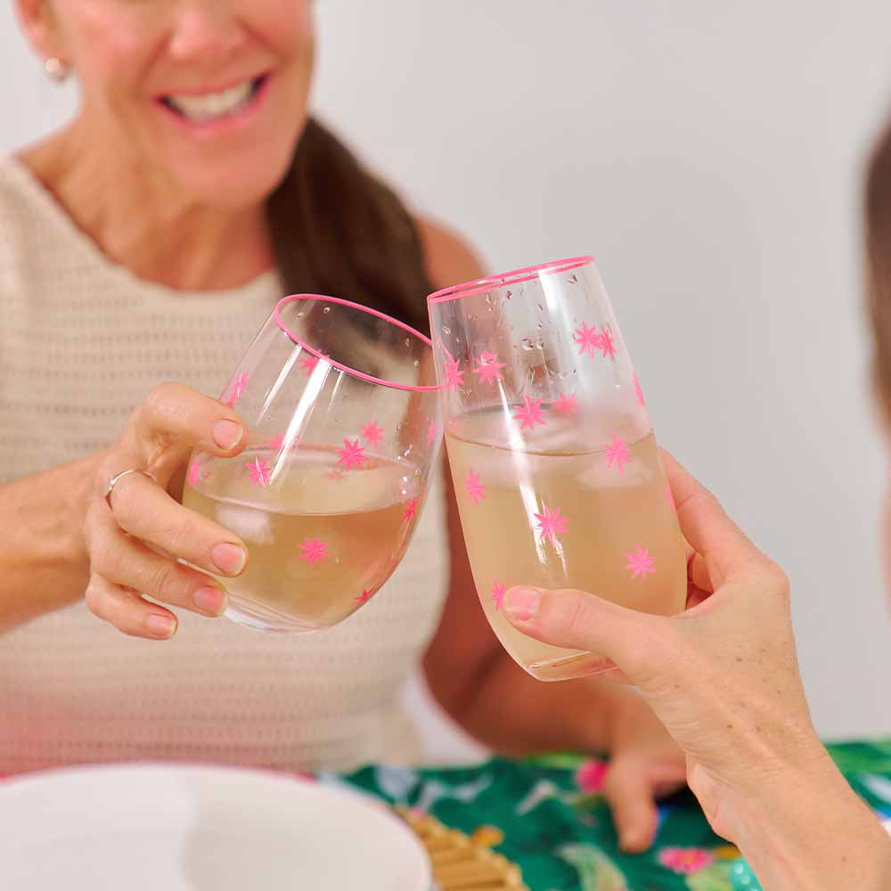 Two people holding glasses of pink champagne with star decorations against a neutral background