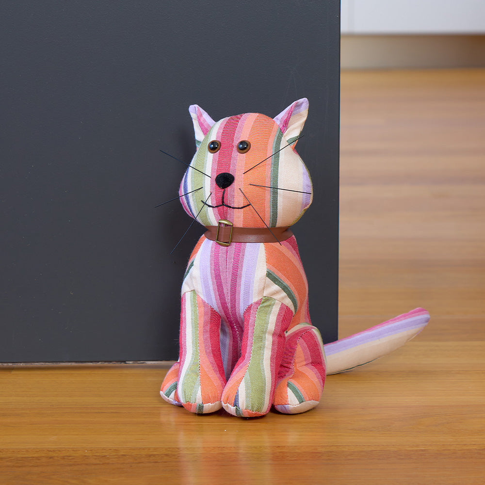 Colorful striped cat-shaped doorstop on a wooden surface with a dark gray background