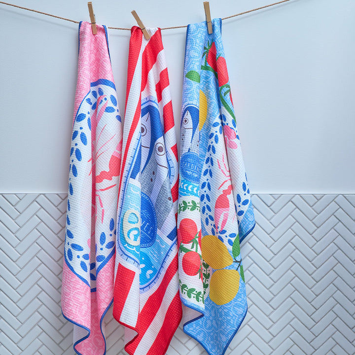 Three colorful towels hanging on a line against a light blue wall.