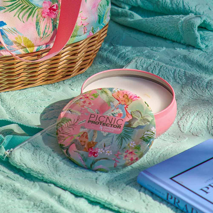 Floral-patterned picnic protector on a turquoise blanket with a basket and book.