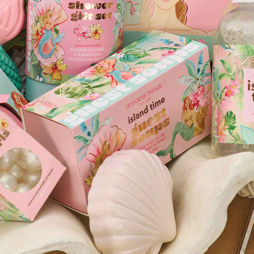 Island-themed soap packaging with floral designs and text on a wooden surface.