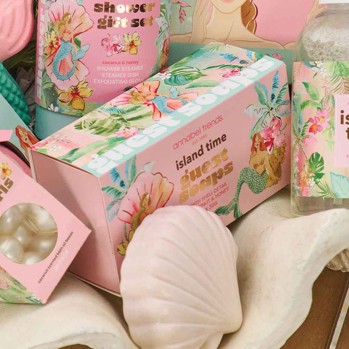 Island-themed soap packaging with floral designs and text on a wooden surface.