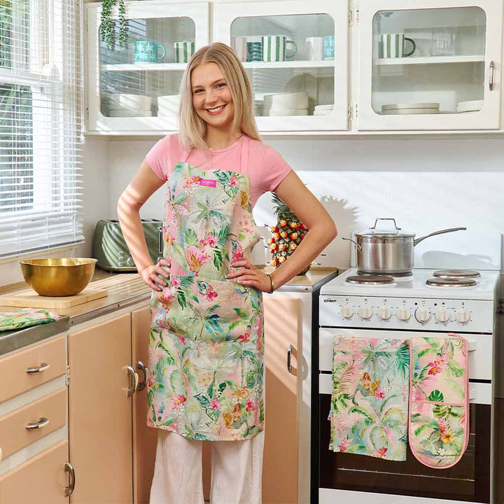 Woman wearing a floral apron and oven mitt in a kitchen