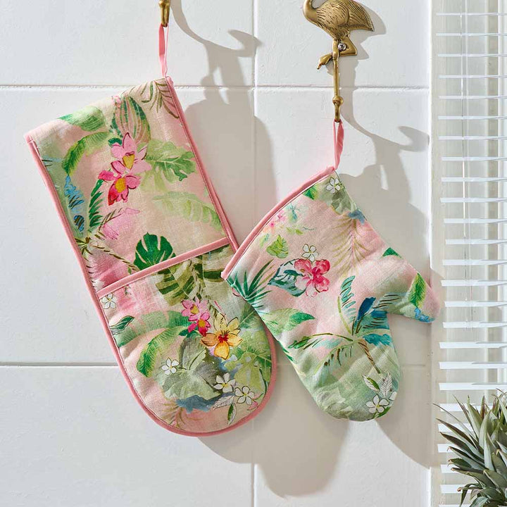 Floral oven mitts hanging on a tiled wall with a decorative flamingo ornament.