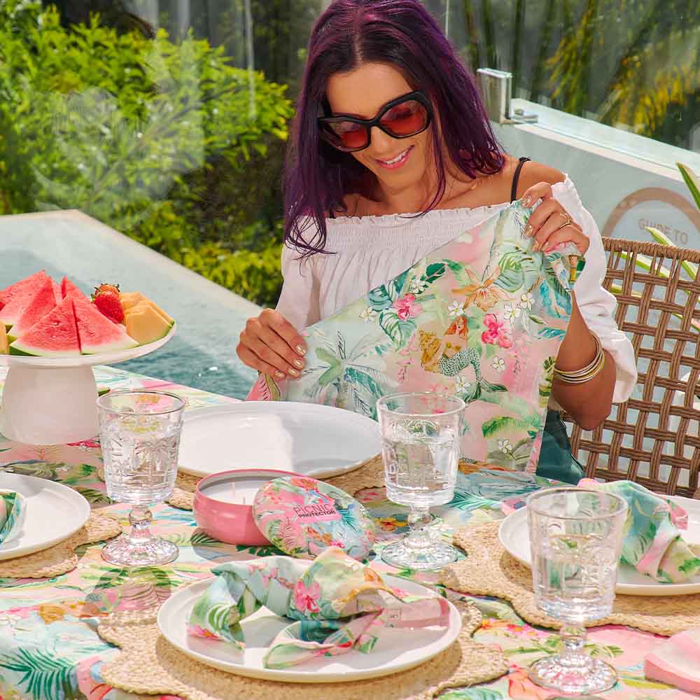 Woman holding a floral dress at a table with a pool and garden in the background