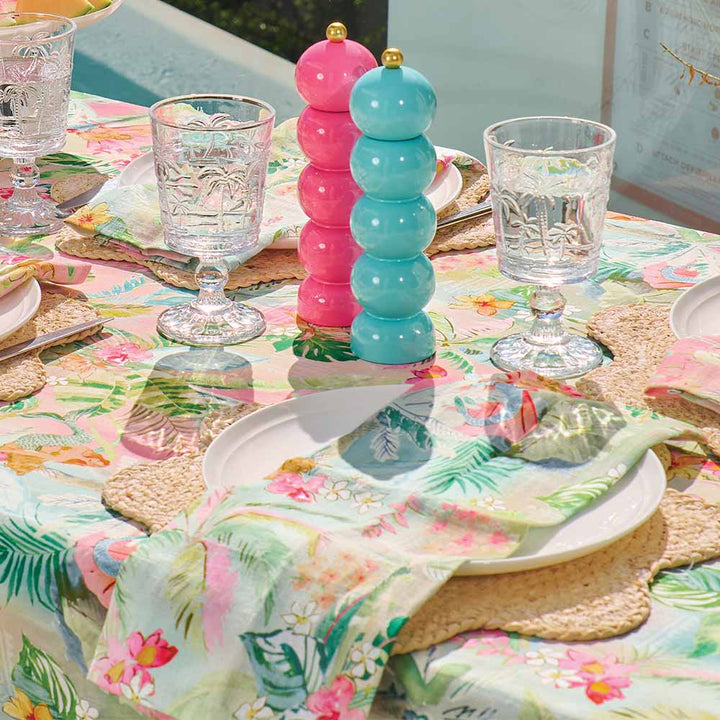 Decorative table setting with floral tablecloth, glasses, and colorful salt and pepper shakers.