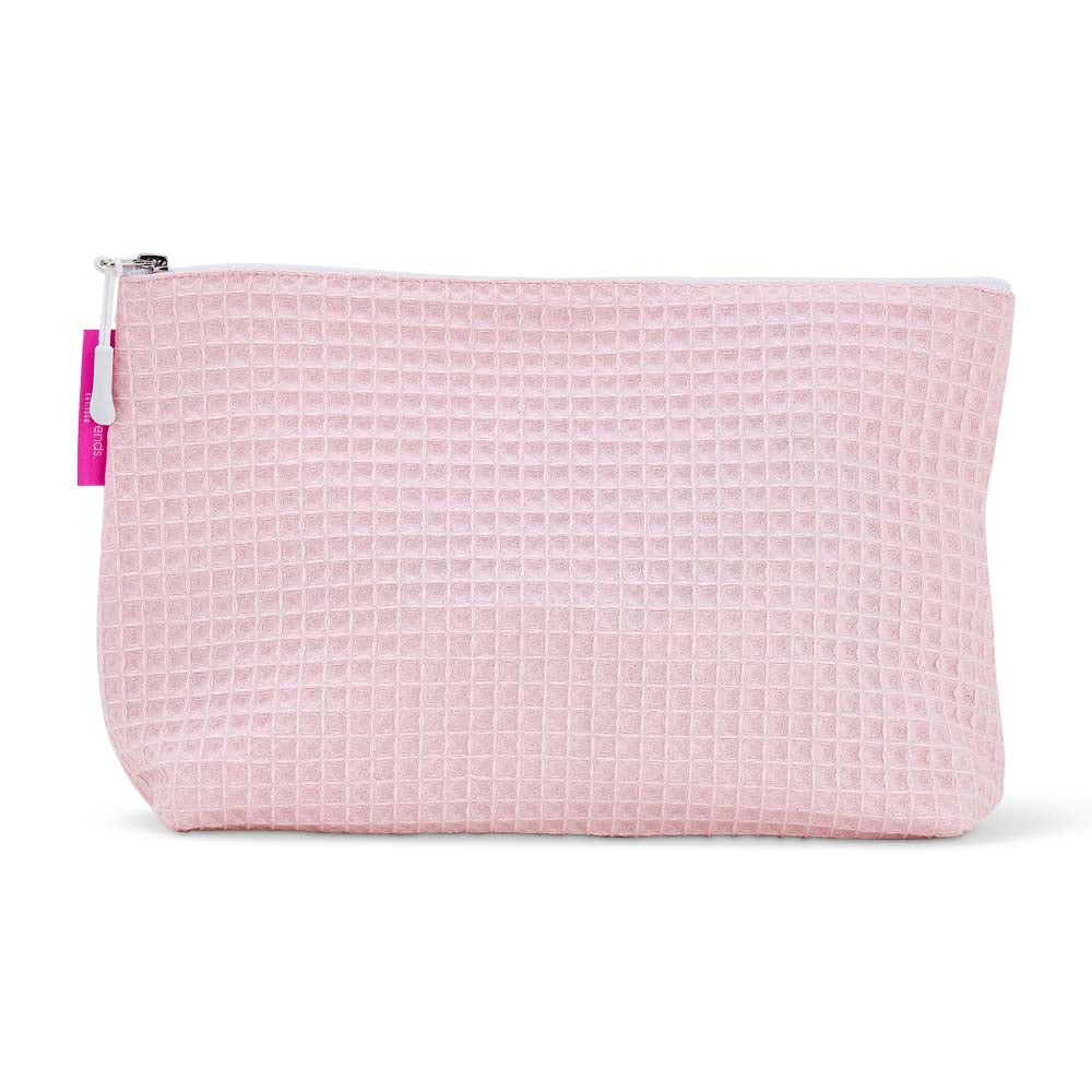 Pink waffle-textured cosmetic bag with a white zipper on a white background