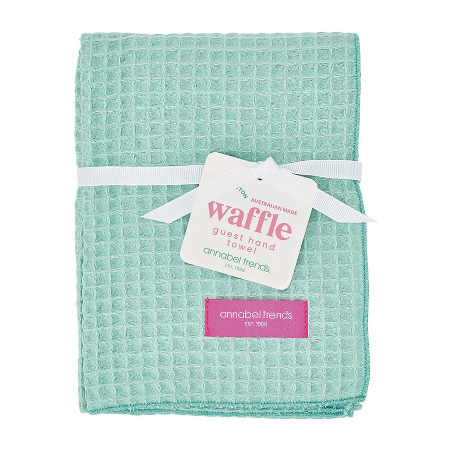 Green waffle towel with a visible brand tag on a white background