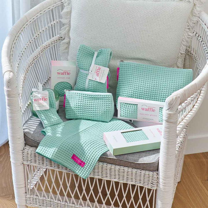 Mint green waffle-textured products on a white wicker chair