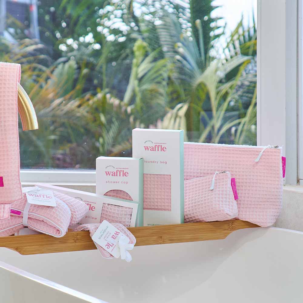 Pink waffle-textured products on a shelf with a window view of greenery