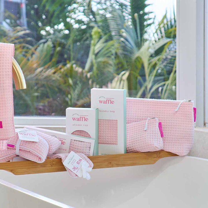 Pink waffle-textured products on a shelf with a window view of greenery
