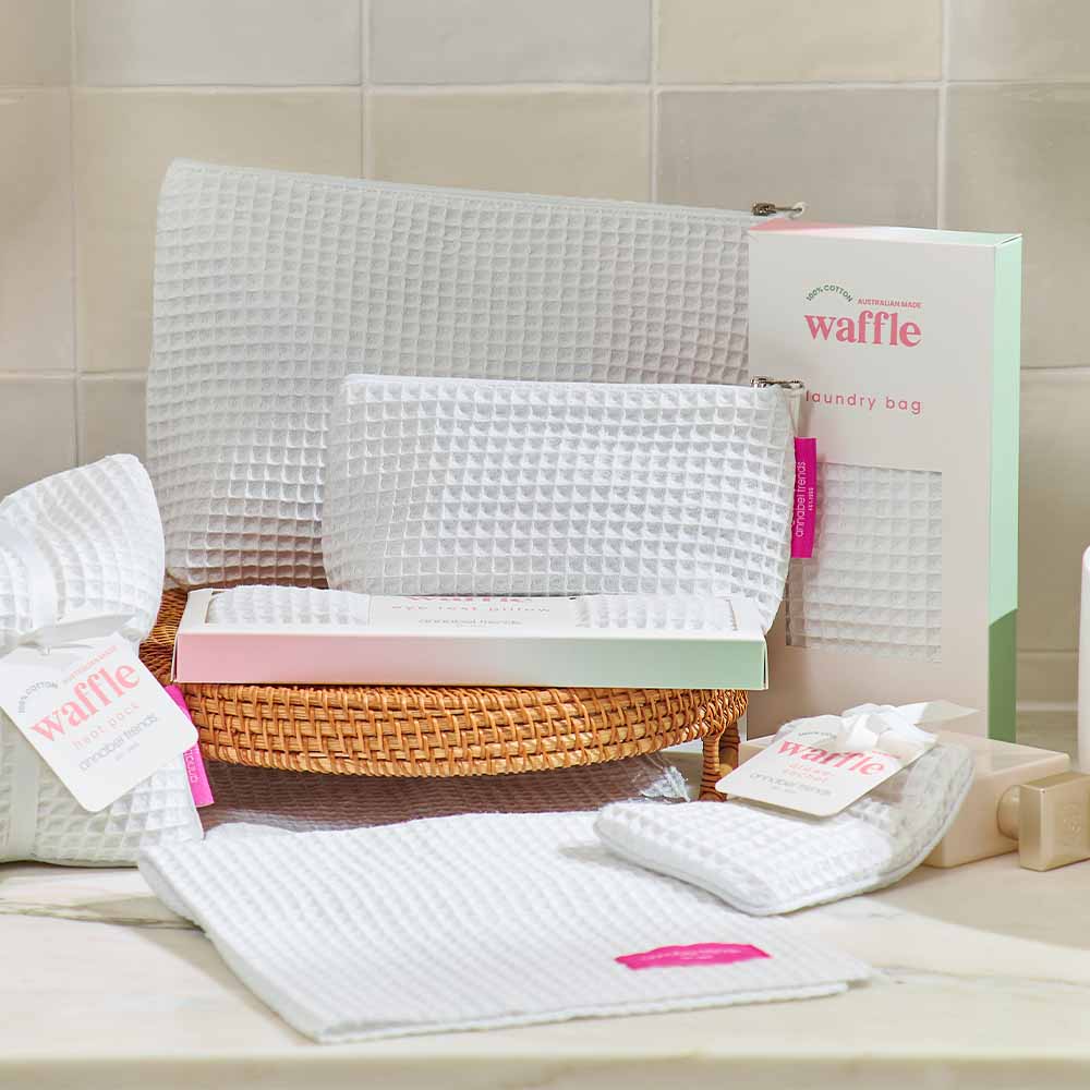 Waffle-textured laundry bags with a wicker basket on a tiled bathroom floor.