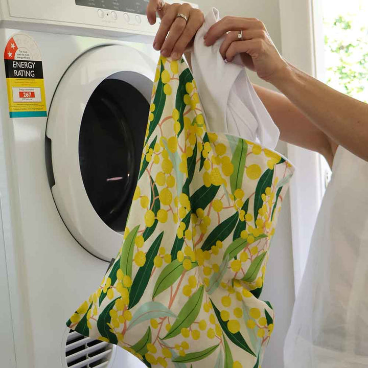 Person holding a floral laundry bag in front of a washing machine