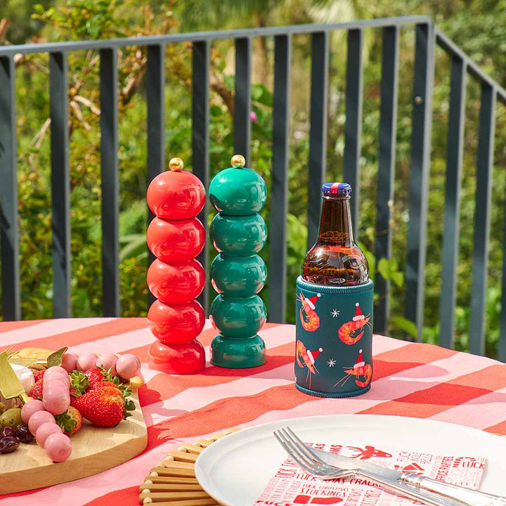 Colorful salt and pepper shakers with a beer bottle on a table outdoors.