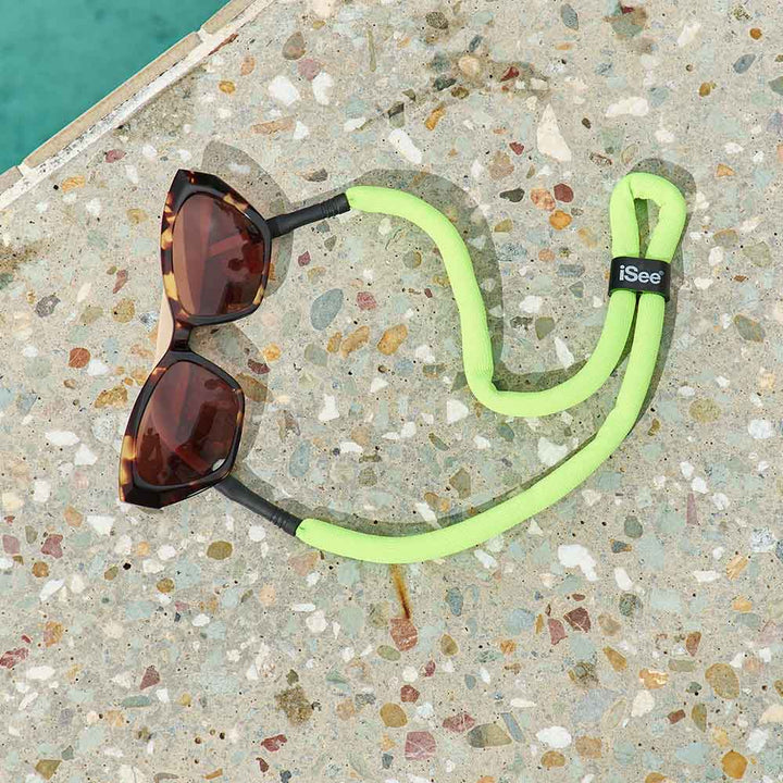 Sunglasses with a green lanyard on a textured surface
