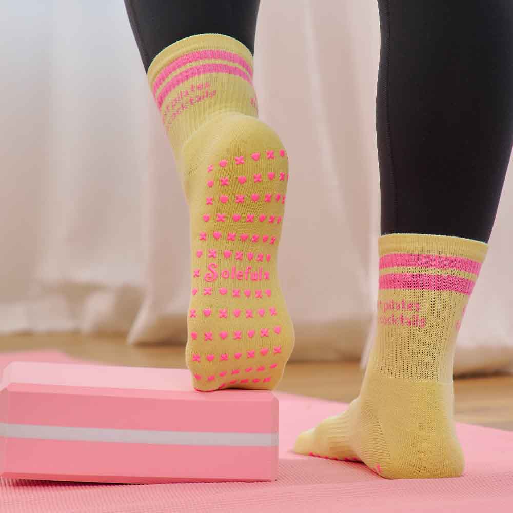 Person wearing yellow socks with pink patterns on a pink step platform.