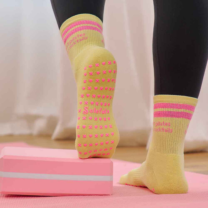 Person wearing yellow socks with pink patterns on a pink step platform.